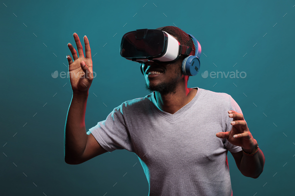 Young guy raising hands to play futuristic game with vr glasses