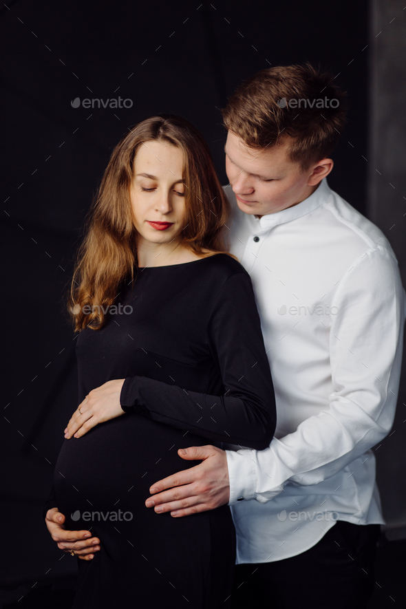 Man in white shirt and female in black dress. Pregnancy photo