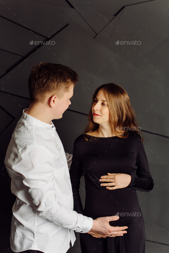 Man in white shirt and female in black dress. Pregnancy photo