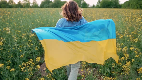Ukrainian Patriot Woman Running with National Flag in Canola Yellow Field alt