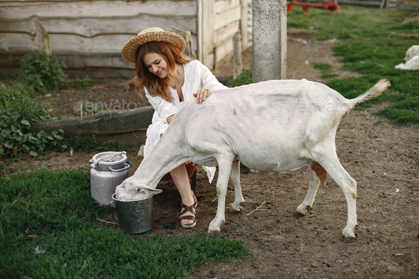 Putdoor portrait of young happy woman with goat - Stock Photo - Images