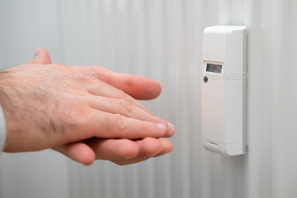 Battery heat meter and man hands demonstrate cold battery. Raising heating and energy prices