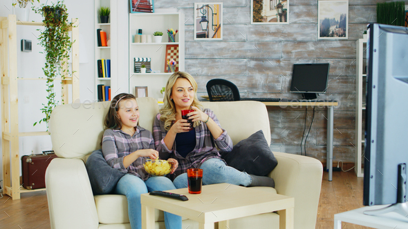 Cheerful mother and daughter sitting on the couch