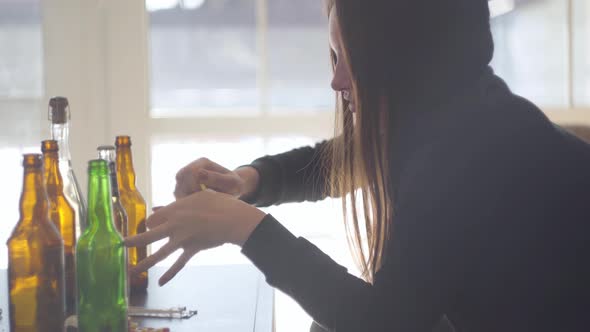 Side View of Young Bad Looking Woman Sniffing Powder From Pills Sitting on the Sofa at Home in Front alt