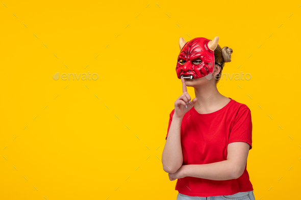 young female wearing scary devil mask asking to be silent yellow background halloween ugly