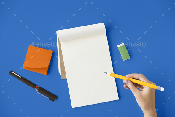 Aerial view of hand holding pencil write notepad on blue table - Stock Photo - Images
