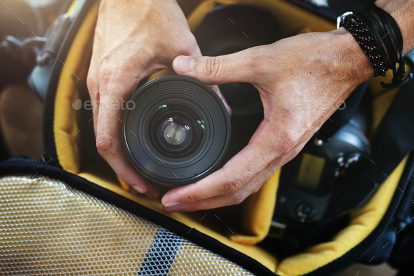 Closeup of hands getting camera lens from bag - Stock Photo - Images