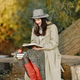 Young woman in a coat sitting on a wooden bench and reading a book - PhotoDune Item for Sale