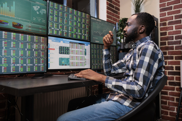 Busy hedge fund trader reviewing financial data and market trend while sitting at workstation