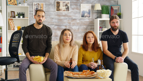 Young man clapping while watching a movie on tv with his friends