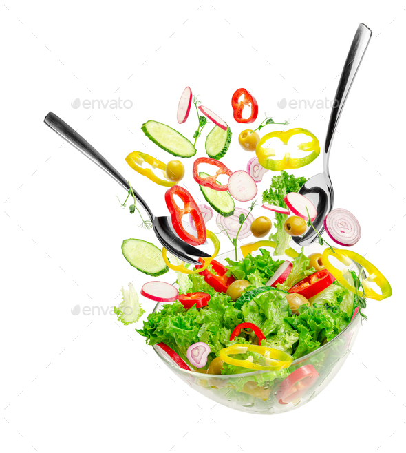 Flying vegetable salad ingredients over transparent bowl with spoon