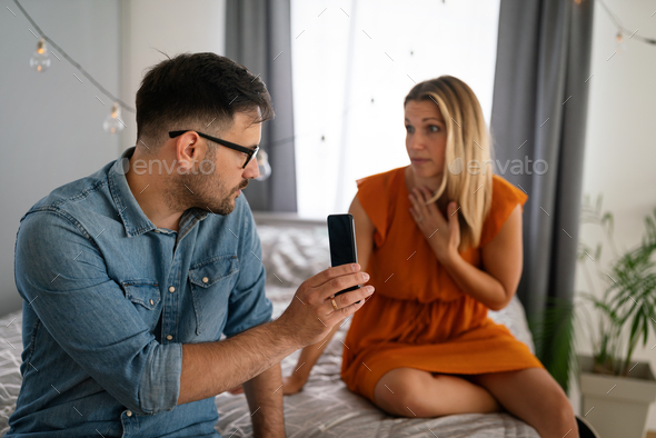 Young couple with smartphone having quarell and marriage conflict because of cheating