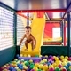 The kid plays in the playroom and rolls down the slide into the pool with small balls - PhotoDune Item for Sale