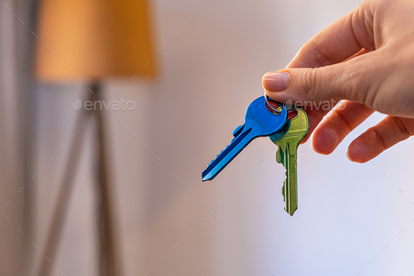 hand holding keys with room on background. rent sell buy apartment real estate business