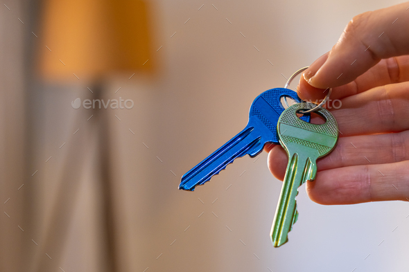 hand holding keys with room on background. rent sell buy apartment real estate business