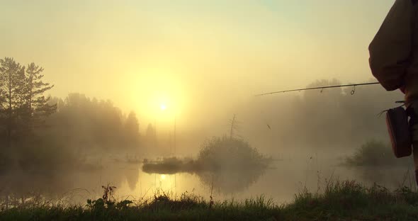 Unrecognizable Man Fishing in Lake at Dawn