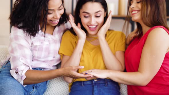 Female hand of happy bride with engagement ring showing it to friends at home alt
