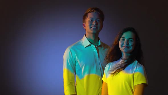 Happy Two Teenagers Posing in Studio with Projector Reflection of Blue and Yellow Ukrainian Flag