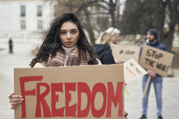 Young caucasian woman standing with manifestation banner on cardboard - Stock Photo - Images