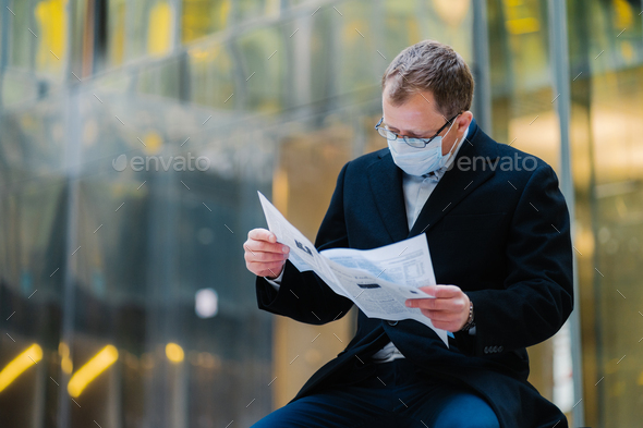Serious Man Reads Newspaper Attentively Poses Against Blurred Building Background Stock Photo By Studiovk