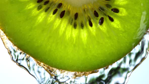 Super Slow Motion Macro Shot of Flowing Water From Kiwi Slice on White Background at 1000Fps alt