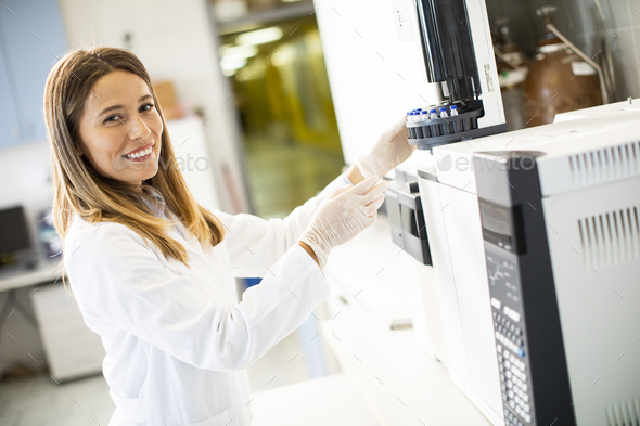 female scientist in a white lab coat putting vial with a sample for an analysis - Stock Photo - Images