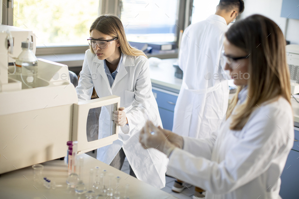 Young female scientists in a white lab coat putting - Stock Photo - Images