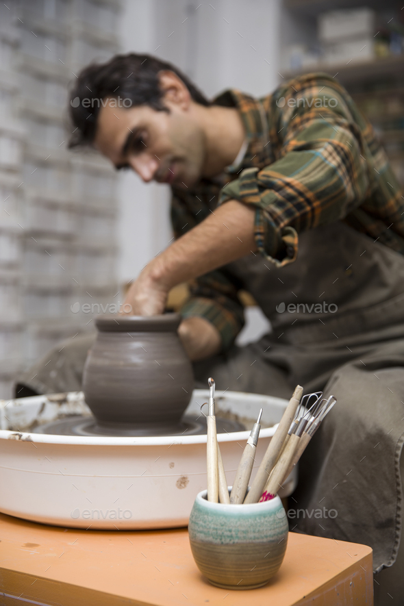 Artist makes clay pottery on a spin wheel in workshop