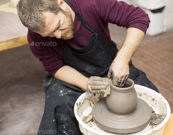 Male artist makes clay pottery on a spin wheel