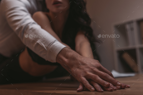 cropped view of businessman hugging sexy secretary and touching her hand