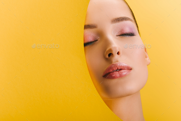 portrait of beautiful woman with shiny makeup in paper round hole with closed eyes isolated on