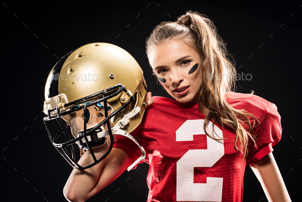 Attractive female american football player in uniform posing with helmet  and looking at camera Stock Photo by LightFieldStudios