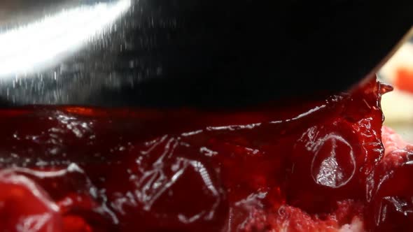 Closeup of a Metal Shiny Spoon Cuts Off Some of the Red Cheesecake and Leaves a Beautiful