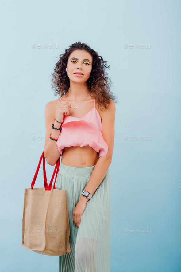 lady with the bag. with curly hair, wearing them in pink shirt,