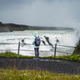 Woman with backpack and green jacket visit Gullfoss powerful famous waterfall in Iceland. Tourist - PhotoDune Item for Sale