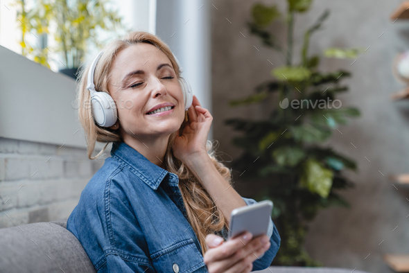 Female enjoying music with eyes closed in headphones earphones, listening to radio podcast e-book