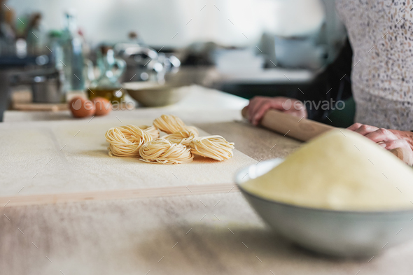 Woman working inside pasta factory doing fresh made tagliatelle