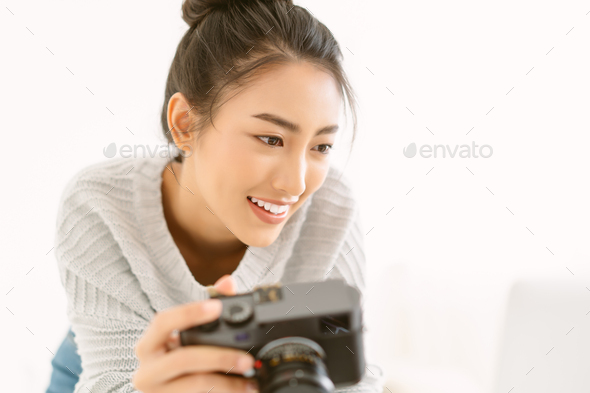 Asian woman photographer with her professional camera and check photo on laptop computer - Stock Photo - Images