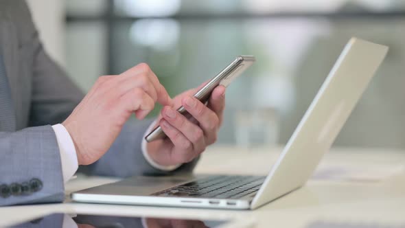 Close Up of Businessman Using Smartphone Near Laptop alt