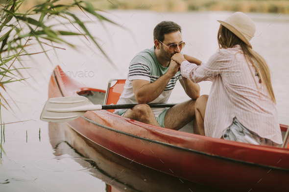 Loving man kissing hands to his woman in boat on the lake