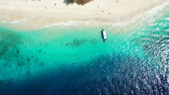Deep blue sea and turquoise lagoon waving on white sand of exotic beach, anchored boat floating over alt