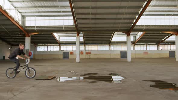 BMX rider in an empty warehouse alt