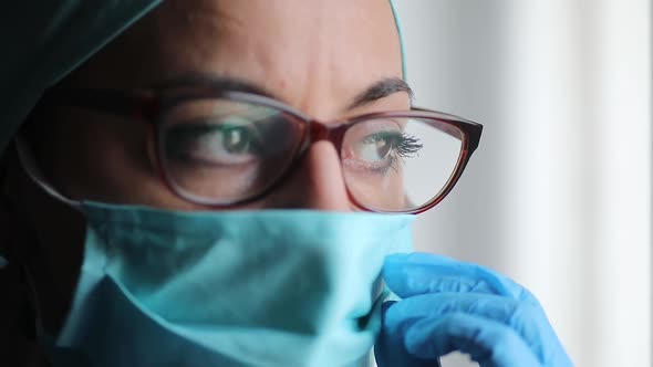 Woman doctor adjusting a surgical mask and glasses