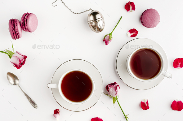 Tea on white table with roses and macaroons for two.