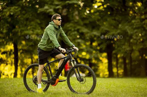 Young man riding ebike in the park - Stock Photo - Images