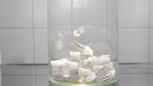 Modern Dentistry Concept. Empty Dental Implant Containers Falling Down Within Glass Bowl Symbolizing alt