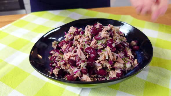 A Woman Eats Salad From a Black Plate alt