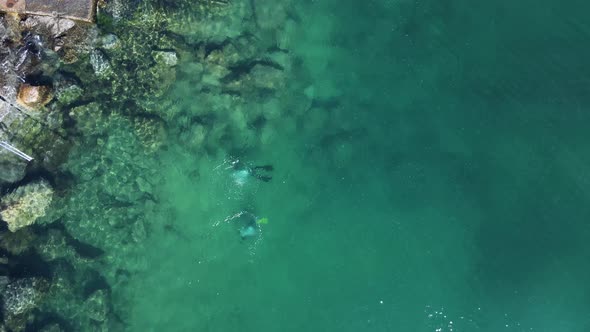 Unique view of scuba divers below the water exploring a man-made artificial reef built for the city alt