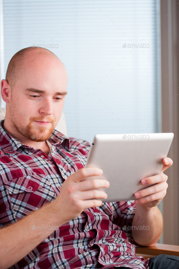 Focused man working and playing with tablet computer (lots of copyspace) - Stock Photo - Images
