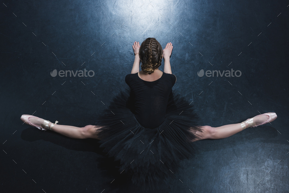 top view of elegant ballerina in pointe shoes and black tutu sitting on twine